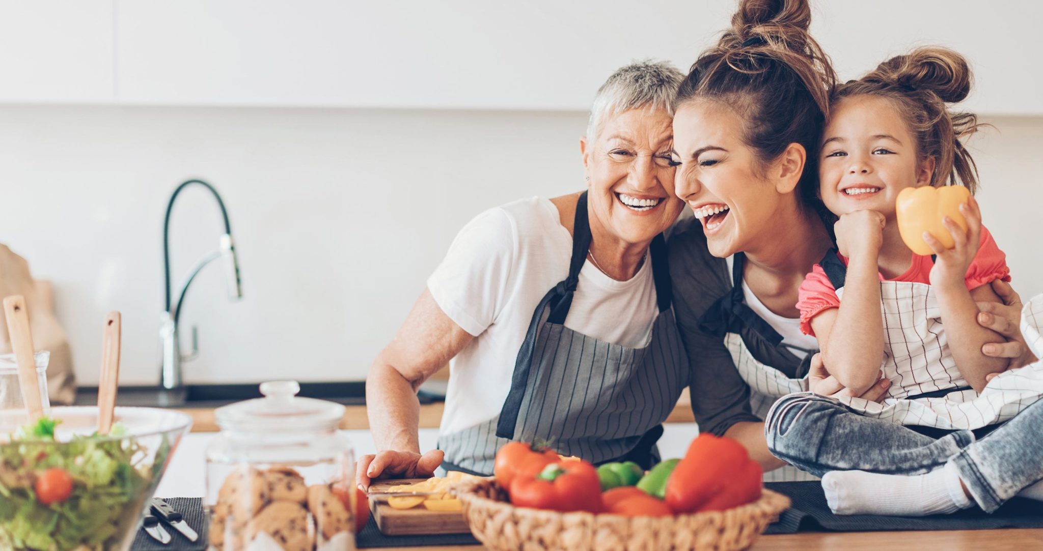 Tres generaciones, dos mujeres y una niña cocinando.